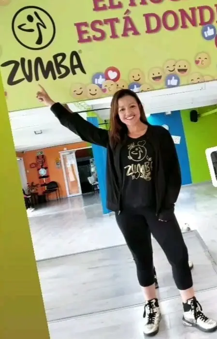 Gina en un espacio de baile con un cartel de Zumba
