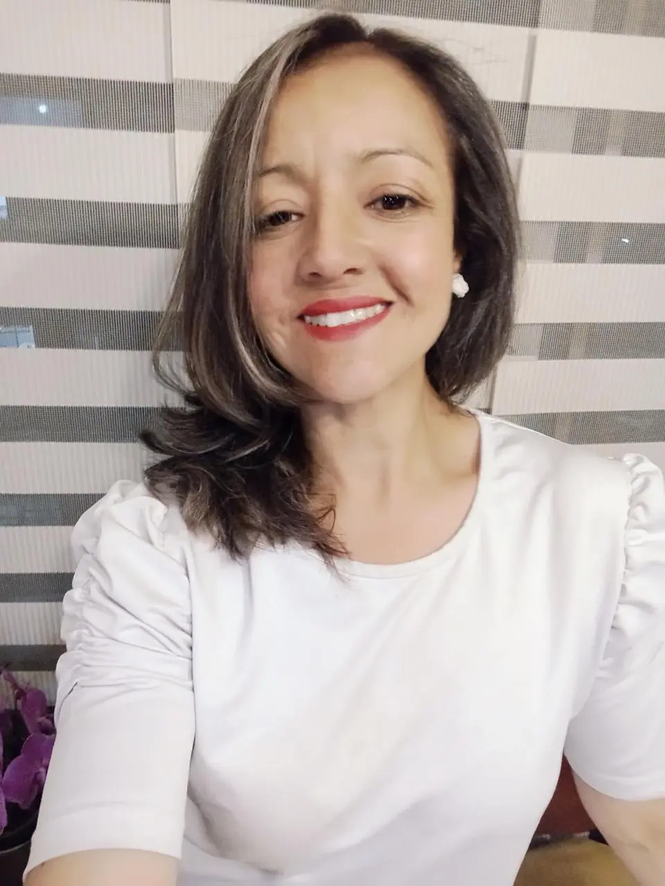 Retrato de Gina Torres, sonriendo con una camiseta blanca